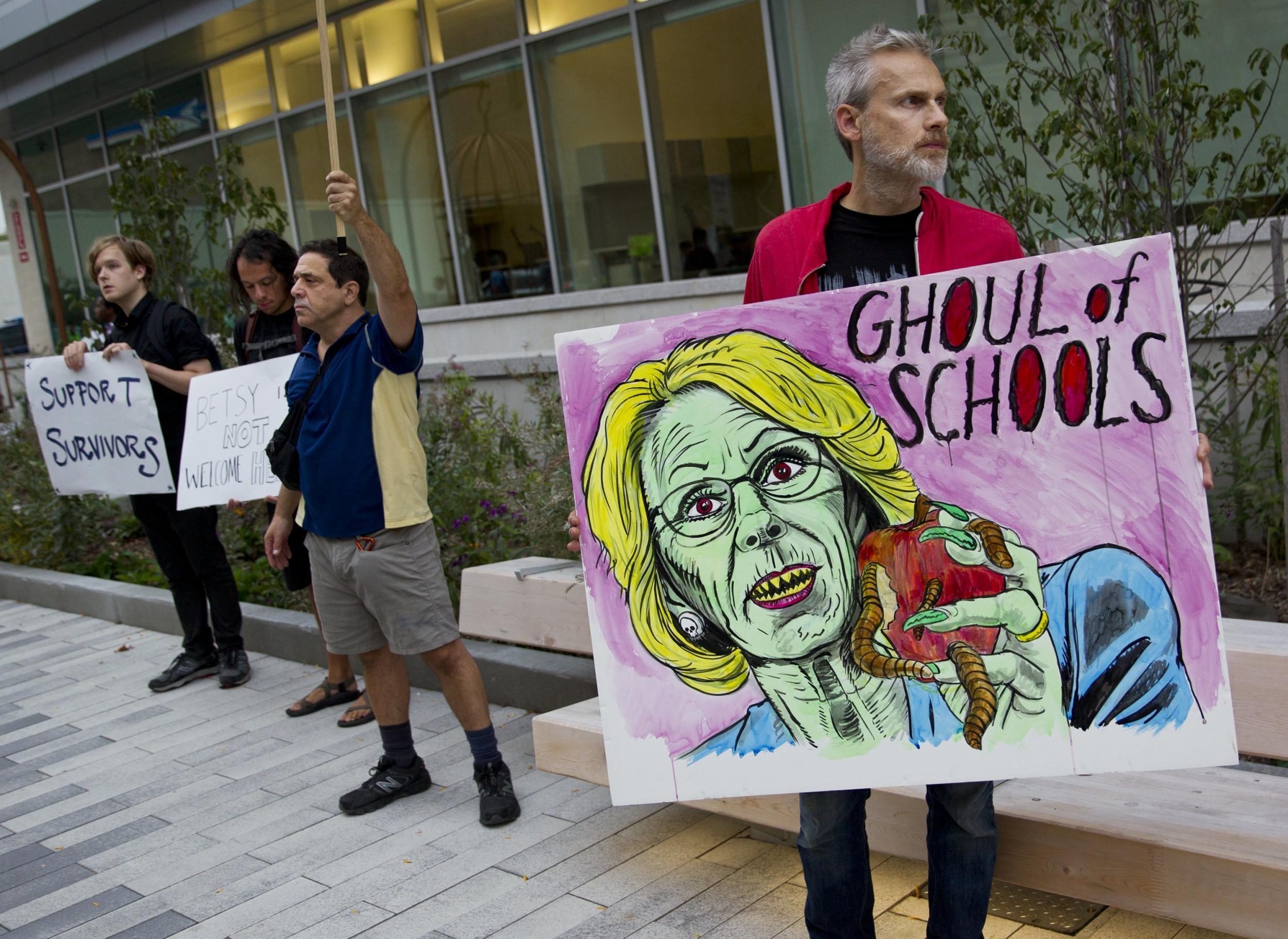 A man protests Education Secretary Betsy DeVos at the dedication ceremony of Michigan State University's new Grand Rapids Medical Research Center