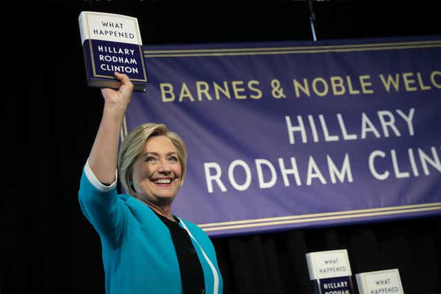 Former US Secretary of State Hillary Clinton holds up a copy of her new book "What Happened" at a book signing event at Barnes and Noble bookstore
