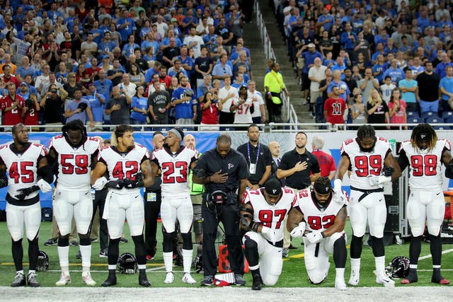 Members of the Atlanta Falcons football team Grady Jarrett and Dontari Poe take a knee during the national anthem while their fellow teammates link arms in solidarity