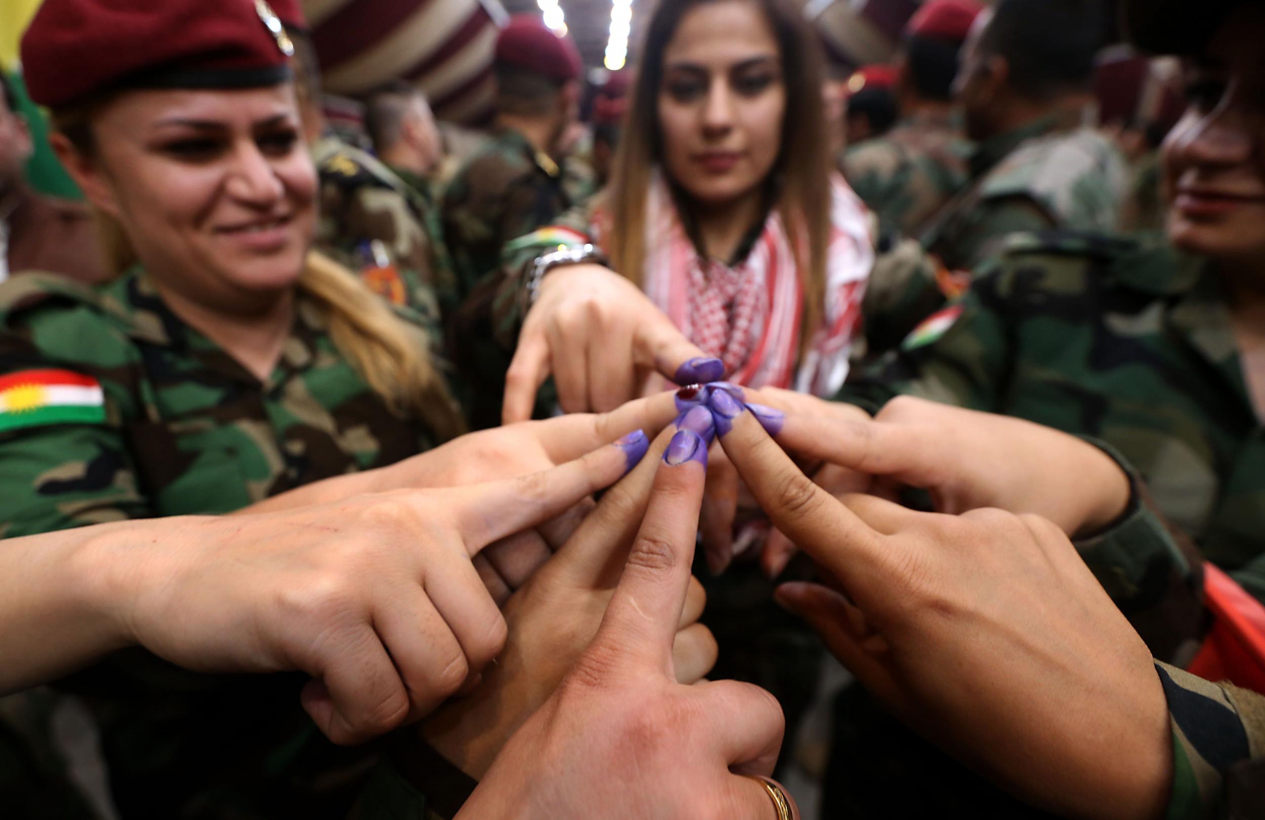 Women from a Kurdish Peshmerga battalion in Irbil show ink-stained fingers after casting their votes on Monday