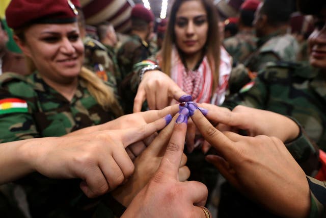 Women from a Kurdish Peshmerga battalion in Irbil show ink-stained fingers after casting their votes on Monday