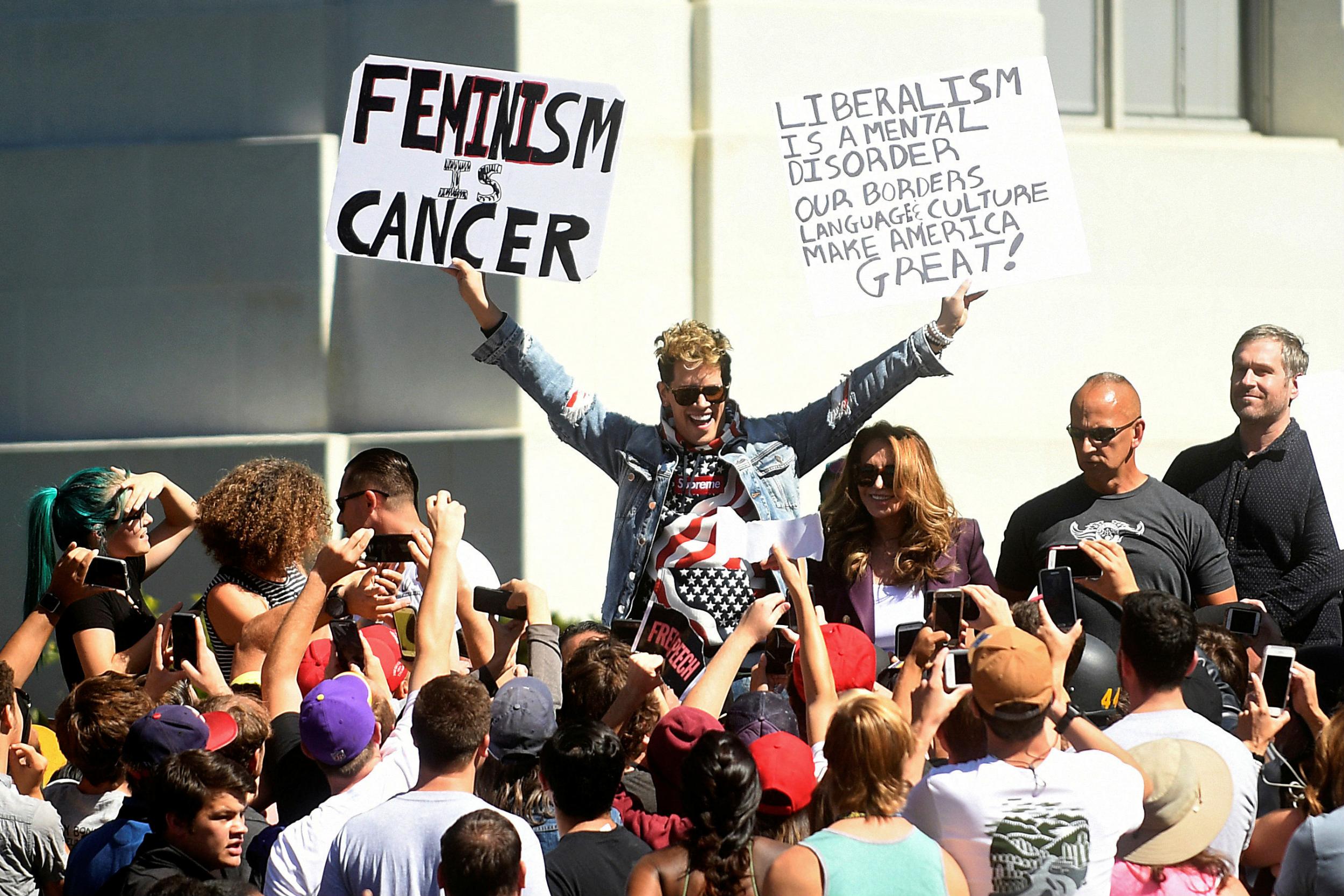 Milo Yiannopoulos holds up characteristically provocative signs while speaking at the University of California in Berkeley, California, September 24, 2017