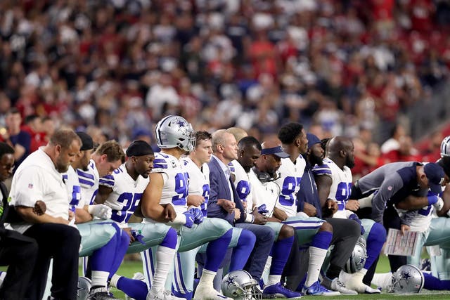 Members of the Dallas Cowboys link arms before the start of their NFL game against the Arizona Cardinals