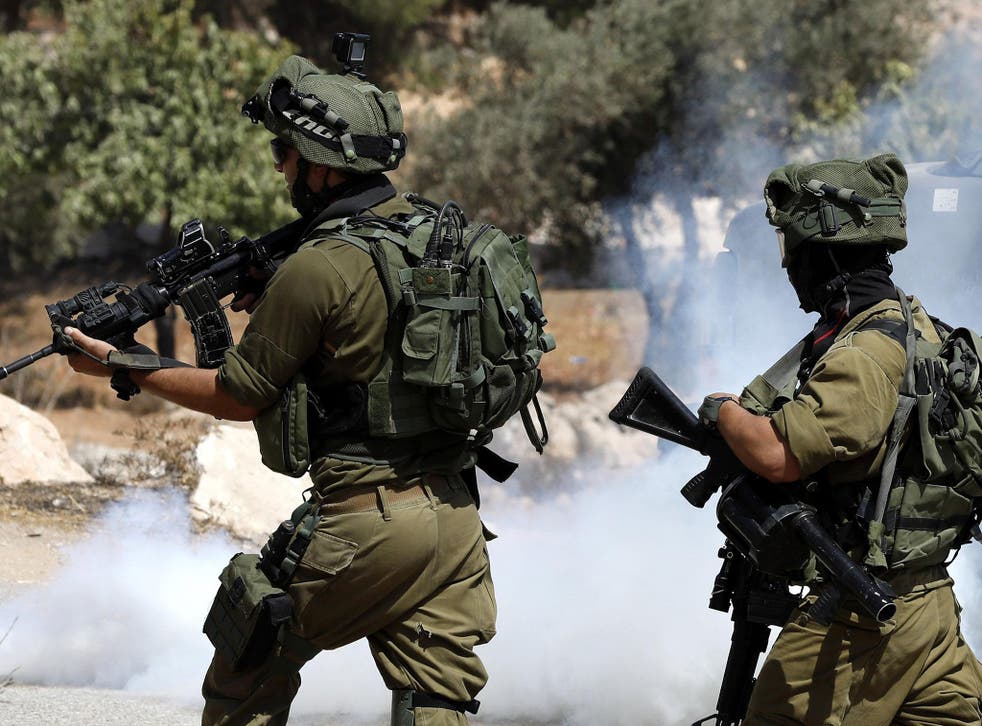 FILE: Israeli soldiers fire tear gas canisters at Palestinians during clashes following a protest against closure of a road south of the West Bank city of Hebron, 22 September 2017