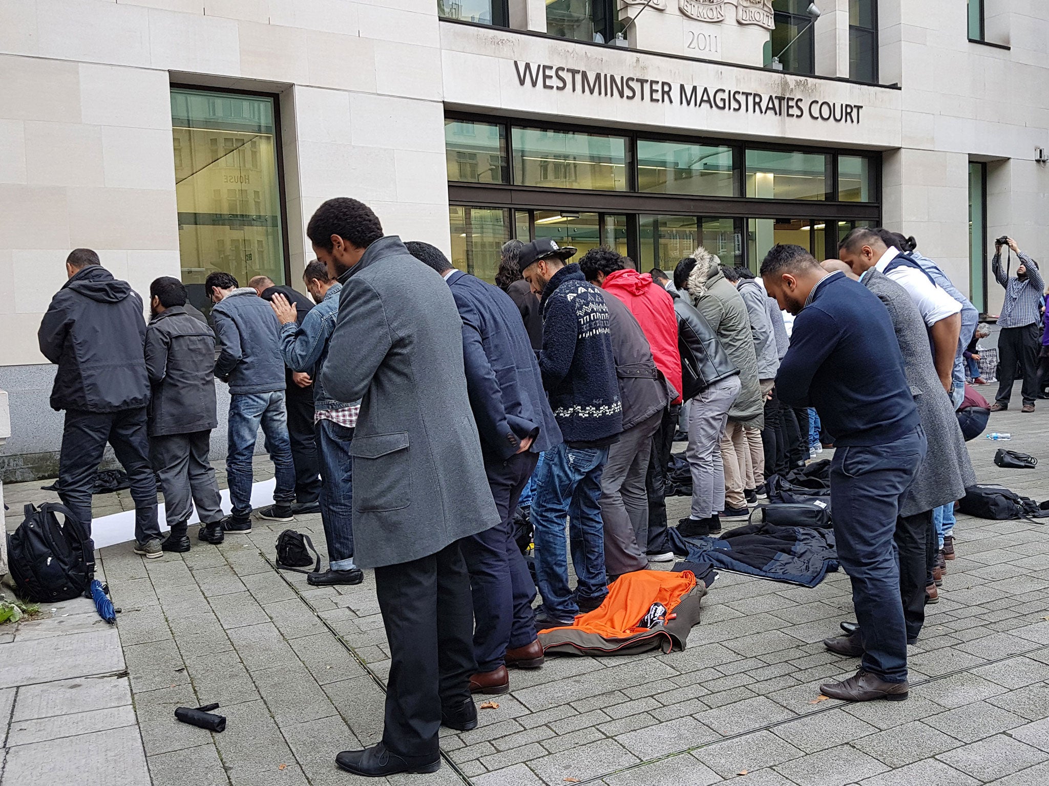 People pray outside Westminster Magistrates' Court during a hearing where Cage director Muhammad Rabbani was convicted of obstructing a police search under terror laws