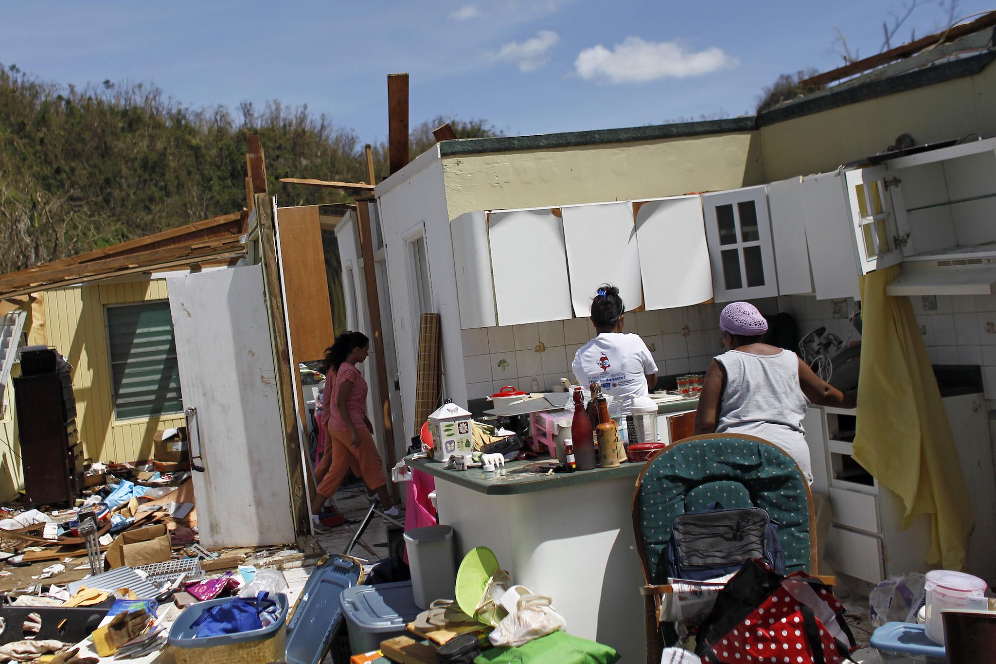 Family members collect belongings after hurricane-force winds destroyed their house in Toa Baja, west of San Juan, Puerto Rico