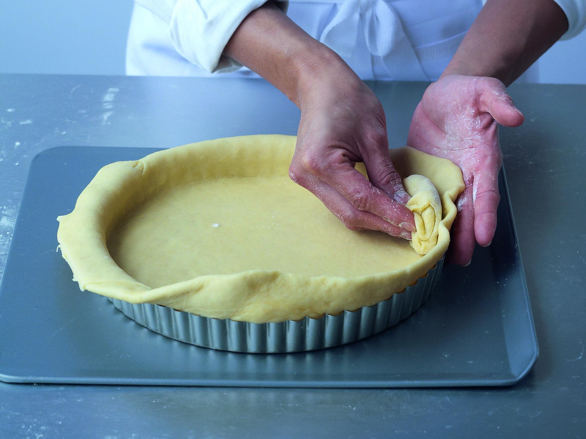 ​4. Tear a small piece from the excess and use it to push the pastry well into the corners. (You could use the side of your knuckle instead.) Ensure the pastry is smoothed up the sides of the flan tin or ring and folded over the edge