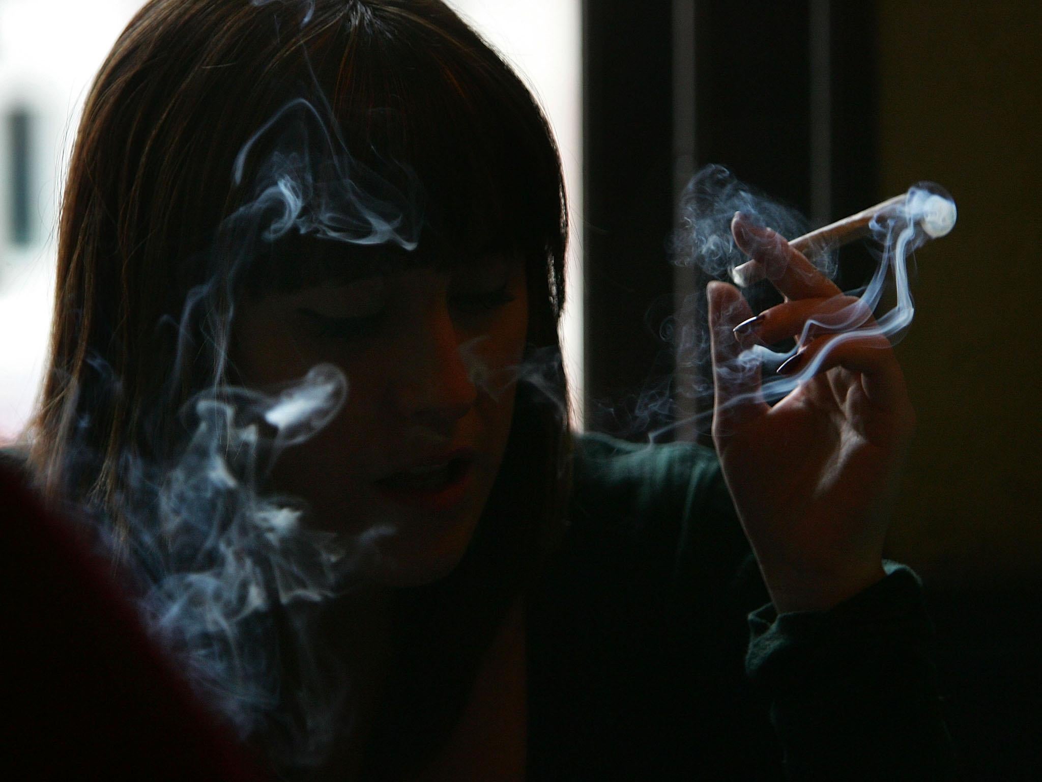 A woman smokes cannabis in Amsterdam, where the city council recently voted to ban smoking marijuana in public areas