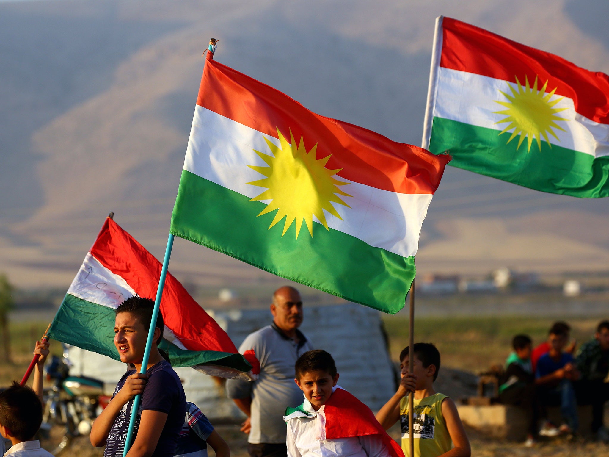 Syrian Kurds wave the Kurdish flag during a gathering in support of the independence referendum