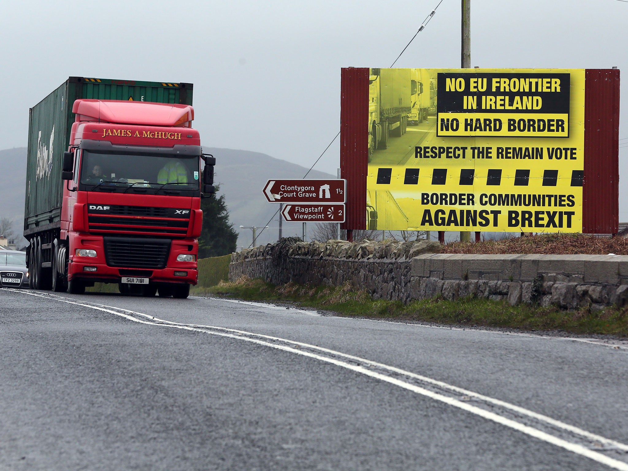 Traffic crosses the border into Northern Ireland from the Irish Republic next to a poster protesting against a hard Brexit