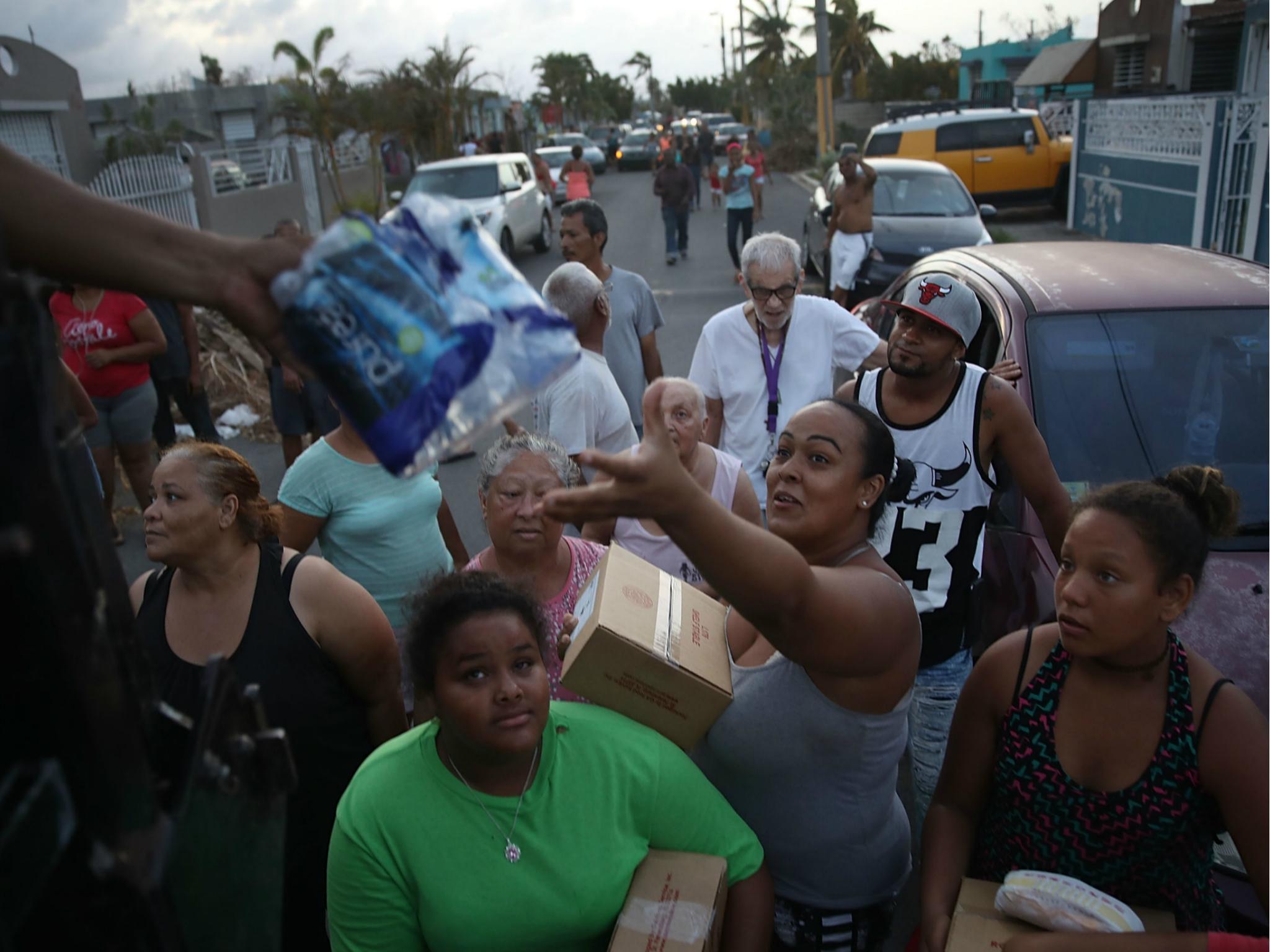 Hurricane survivors receive food and water being given out by volunteers and municipal police as they deal with the aftermath of Hurricane Maria on 28 September 2017 in Toa Baja, Puerto Rico.