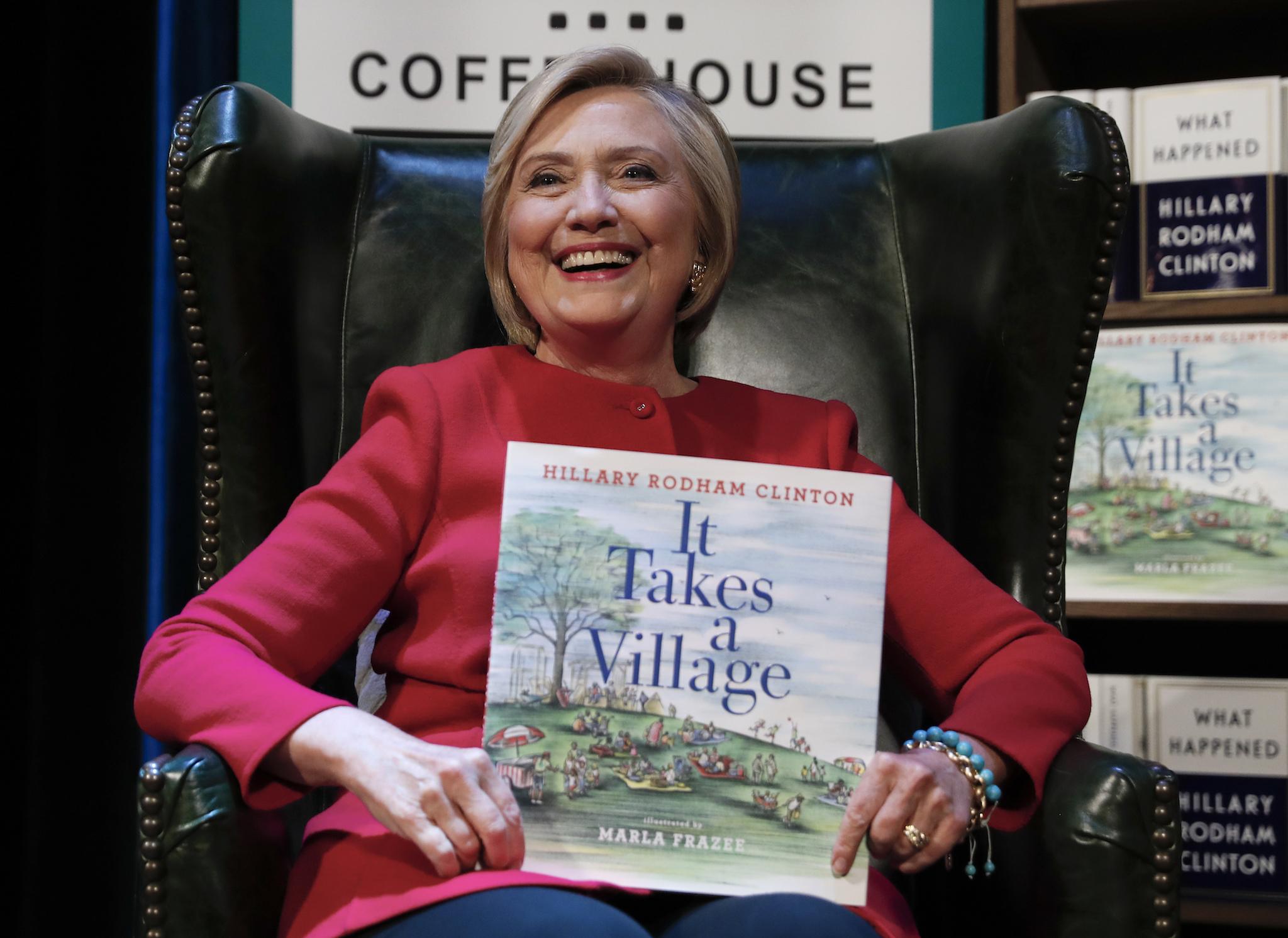 Hillary Clinton, holding her book "It Takes A Village"