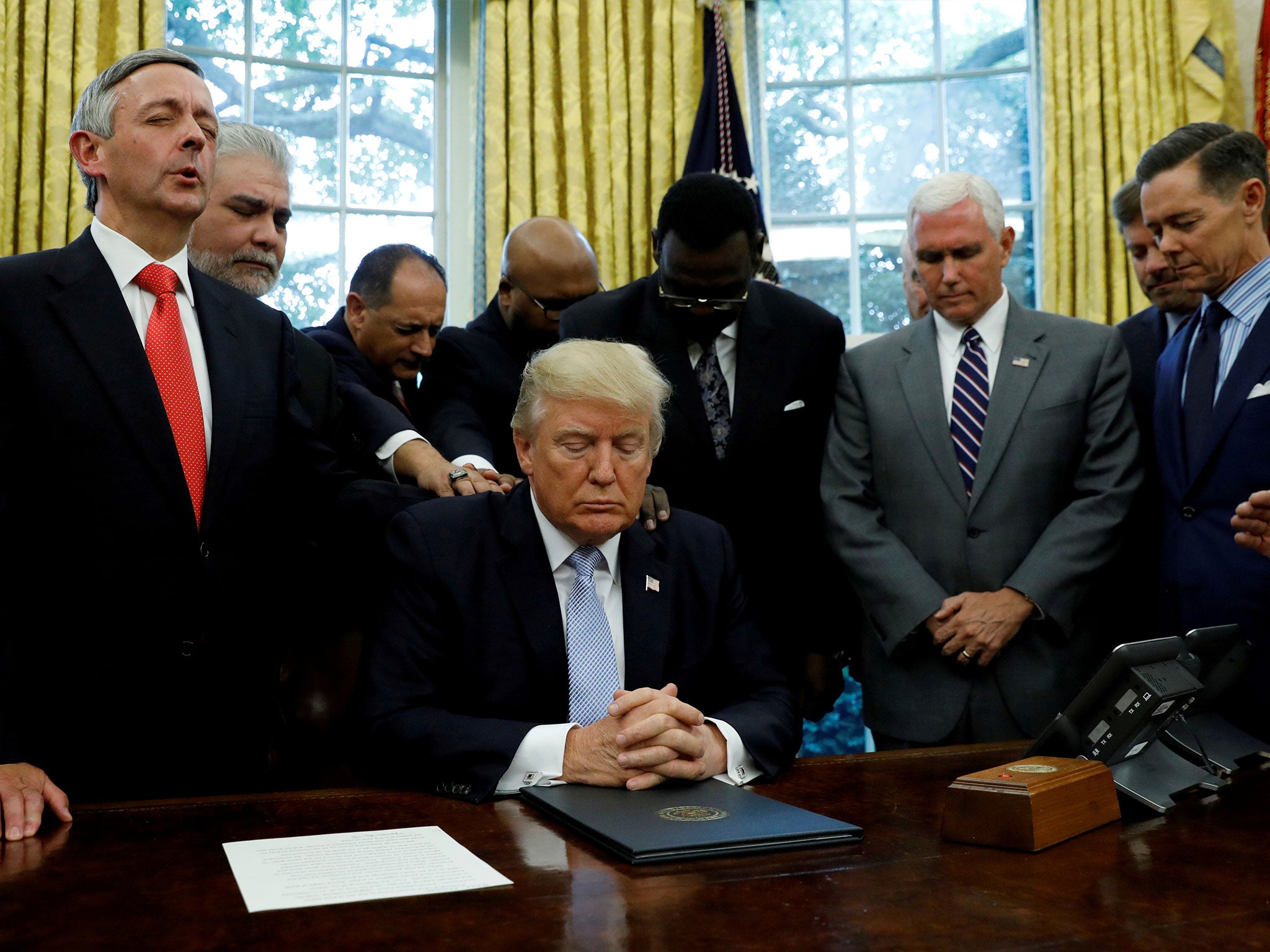 Faith leaders place their hands on the shoulders of Donald Trump as he takes part in a prayer for those affected by Hurricane Harvey earlier this month