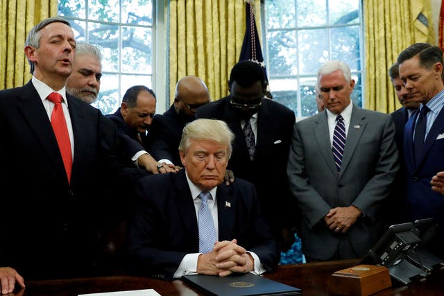 Faith leaders place their hands on the shoulders of Donald Trump as he takes part in a prayer for those affected by Hurricane Harvey earlier this month