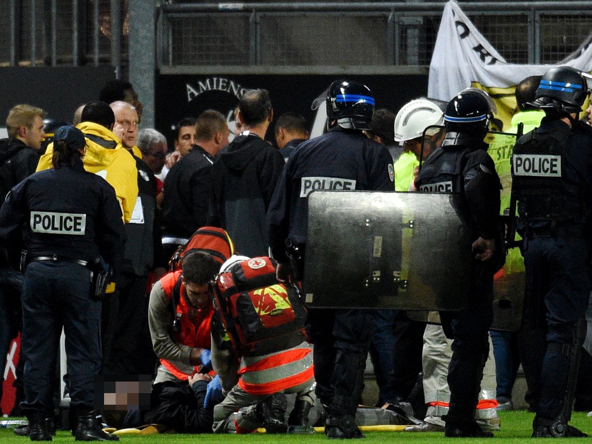 French police officers and members of stadium staff stand by rescuers as they take care of wounded supporters