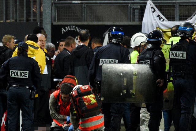 French police officers and members of stadium staff stand by rescuers as they take care of wounded supporters
