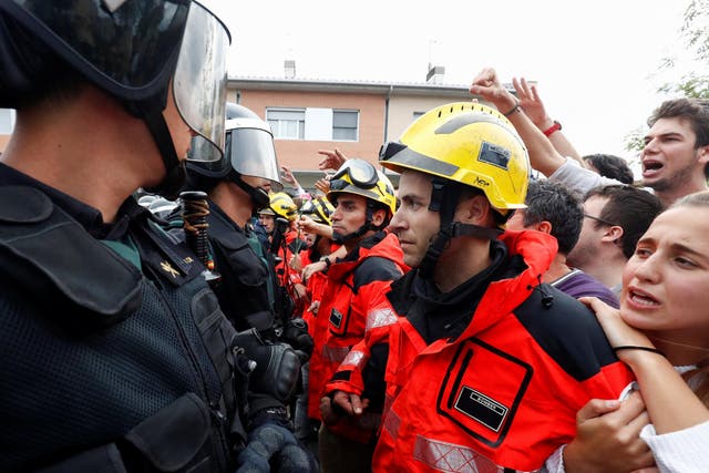 Firemen and people face off Spanish Civil Guard officers outside a polling station for the banned independence referendum in Sant Julia de Ramis