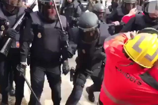 A Catalan firefighter recoils as he is struck by an officer