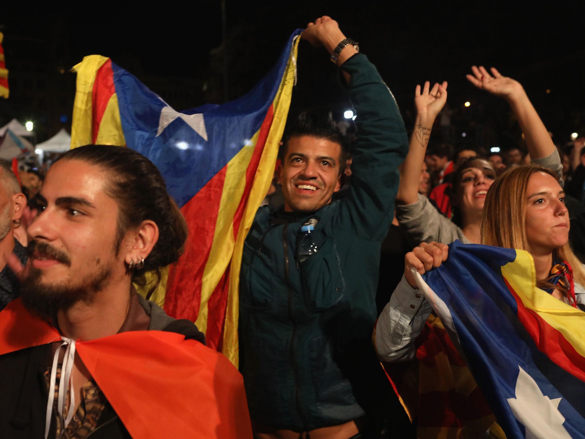 People hold Catalan flags after voting in Catalan referendum at the Placa de Catalunya