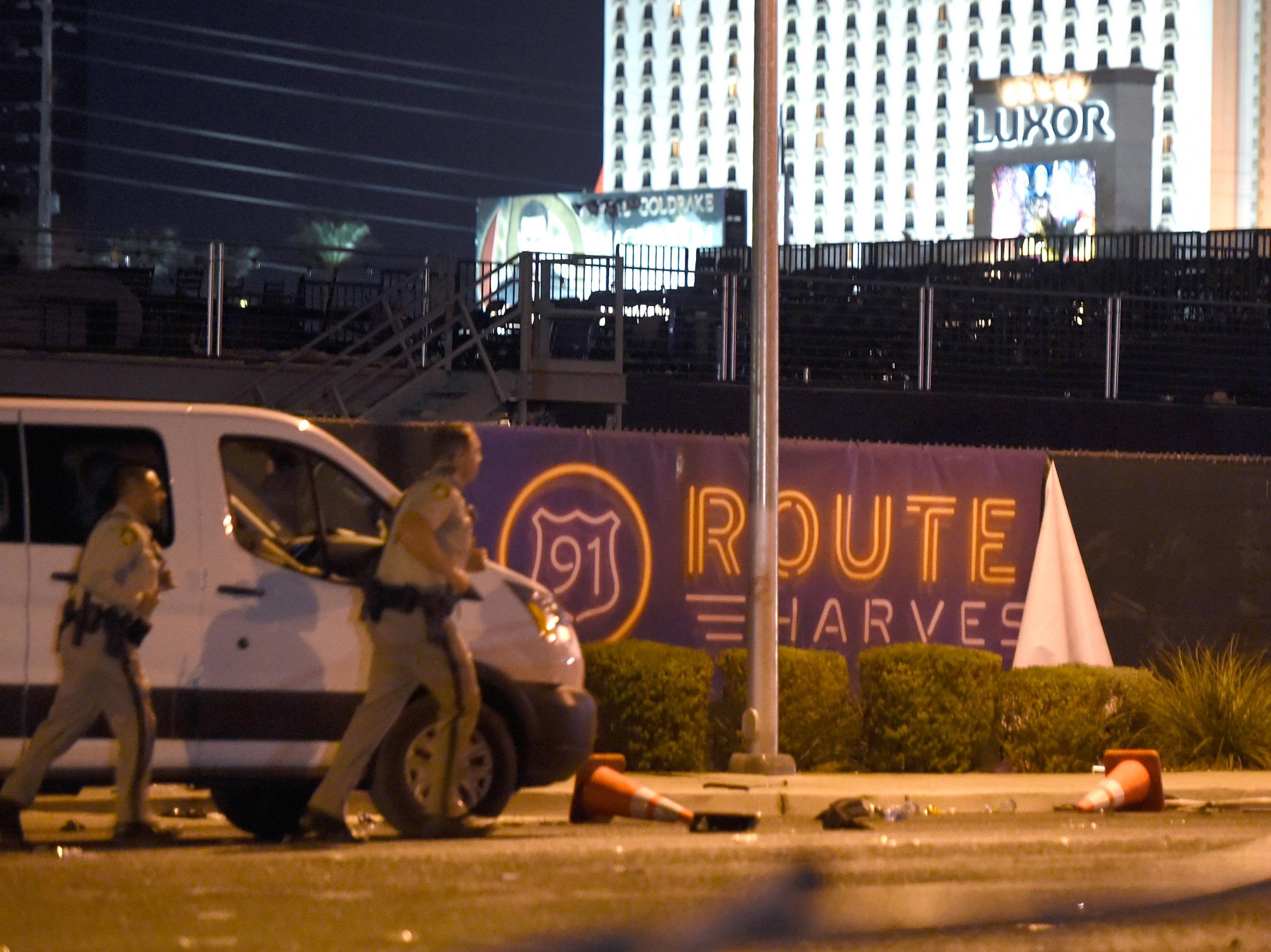 Las Vegas police run by a banner on the fence at the Route 91 Harvest country music festival grounds after shots were fired