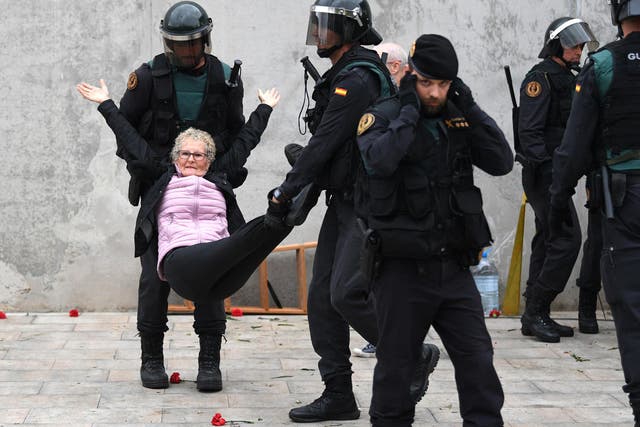 Police carry away an elderly woman after she tried to vote at a polling station in Catalonia