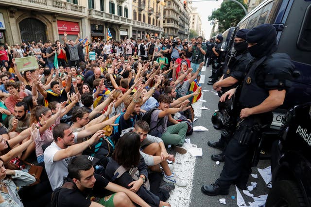 People shout slogans during a protest as Catalan regional police officers stand guard outside National Police station, in Barcelona