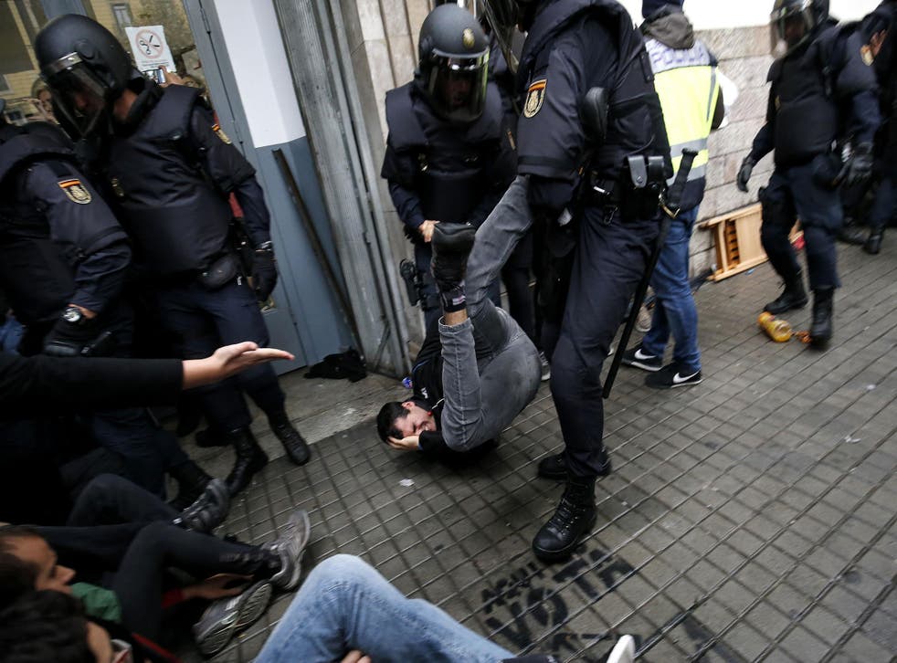 Spanish police officers drag a man from a polling station in Barcelona