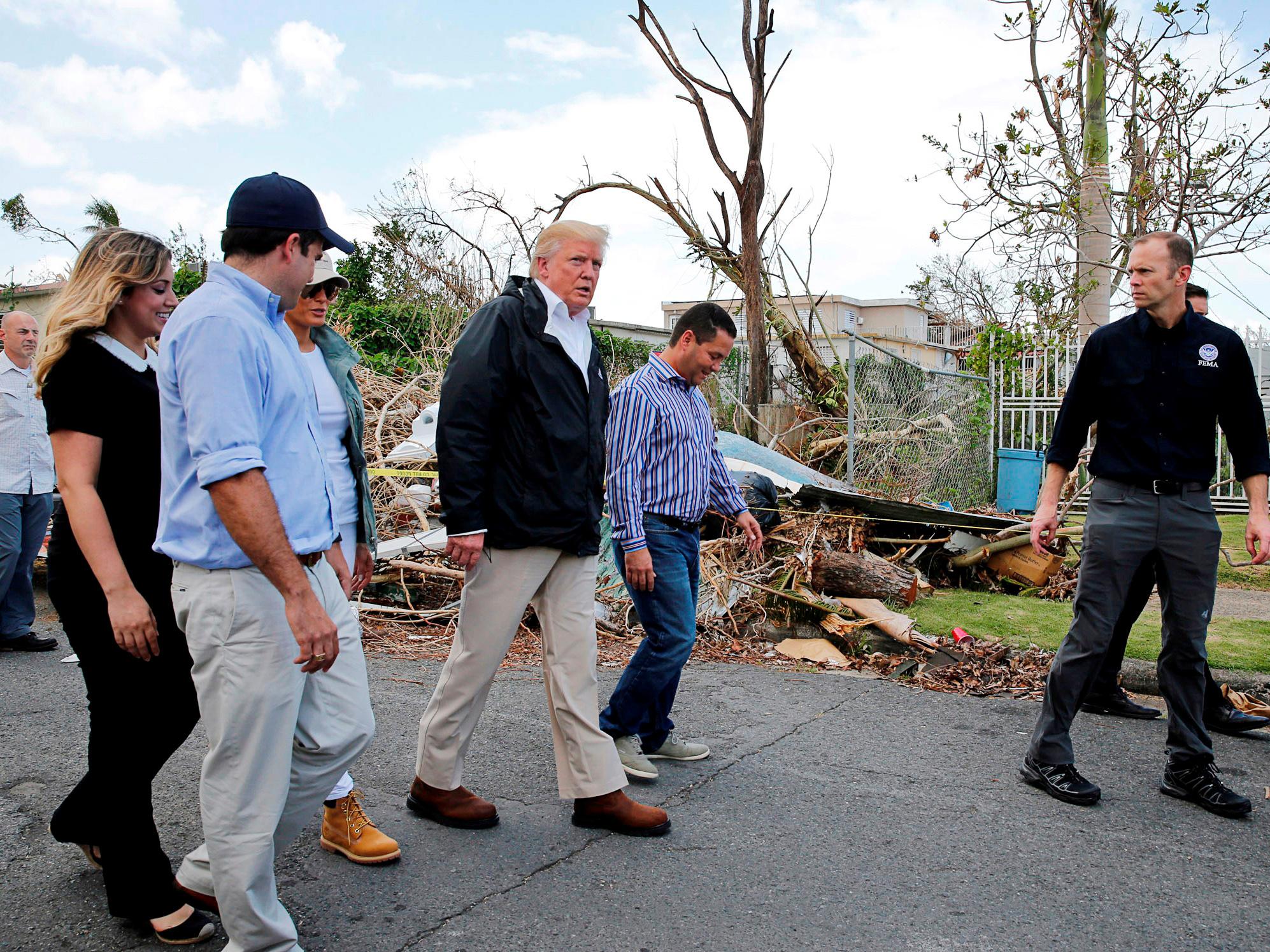 US President Donald Trump walks past hurricane wreckage as he participates in a walking tour with First Lady Melania Trump, Guaynabo Mayor Angel Perez Otero (second right) and Acting FEMA Administrator Brock Long (far right) as well as Puerto Rico Governor Ricardo Rossello (left) and his wife Beatriz Areizeaga in areas damaged by Hurricane Maria