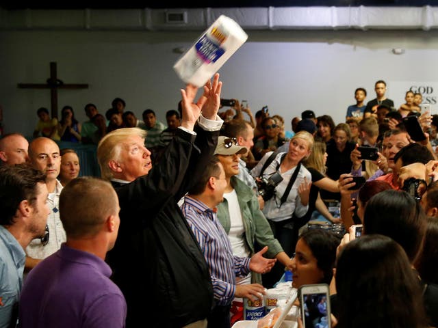 US President Donald Trump tosses rolls of paper towels to people at a hurricane relief distribution centre at Calvary Chapel in San Juan