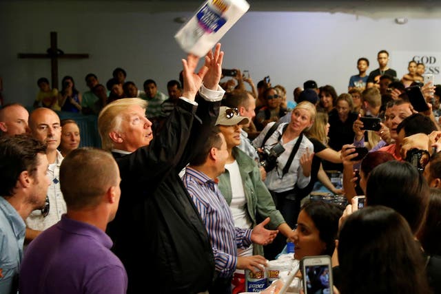 US President Donald Trump tosses rolls of paper towels to people at a hurricane relief distribution centre at Calvary Chapel in San Juan