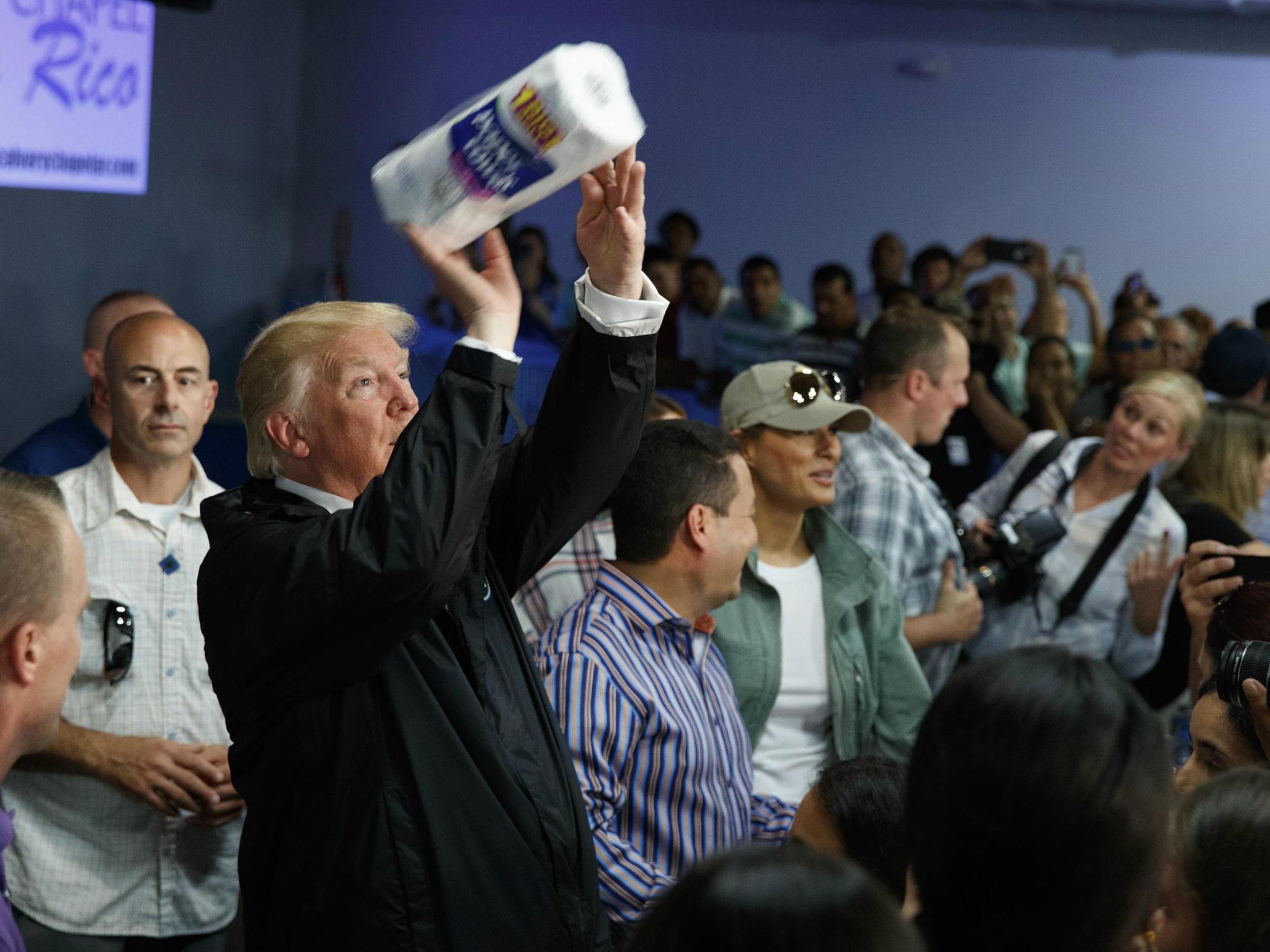 President Donald Trump tosses paper towels into a crowd as he hands out supplies at Calvary Chapel, 3 October, in Guaynabo, Puerto Rico.