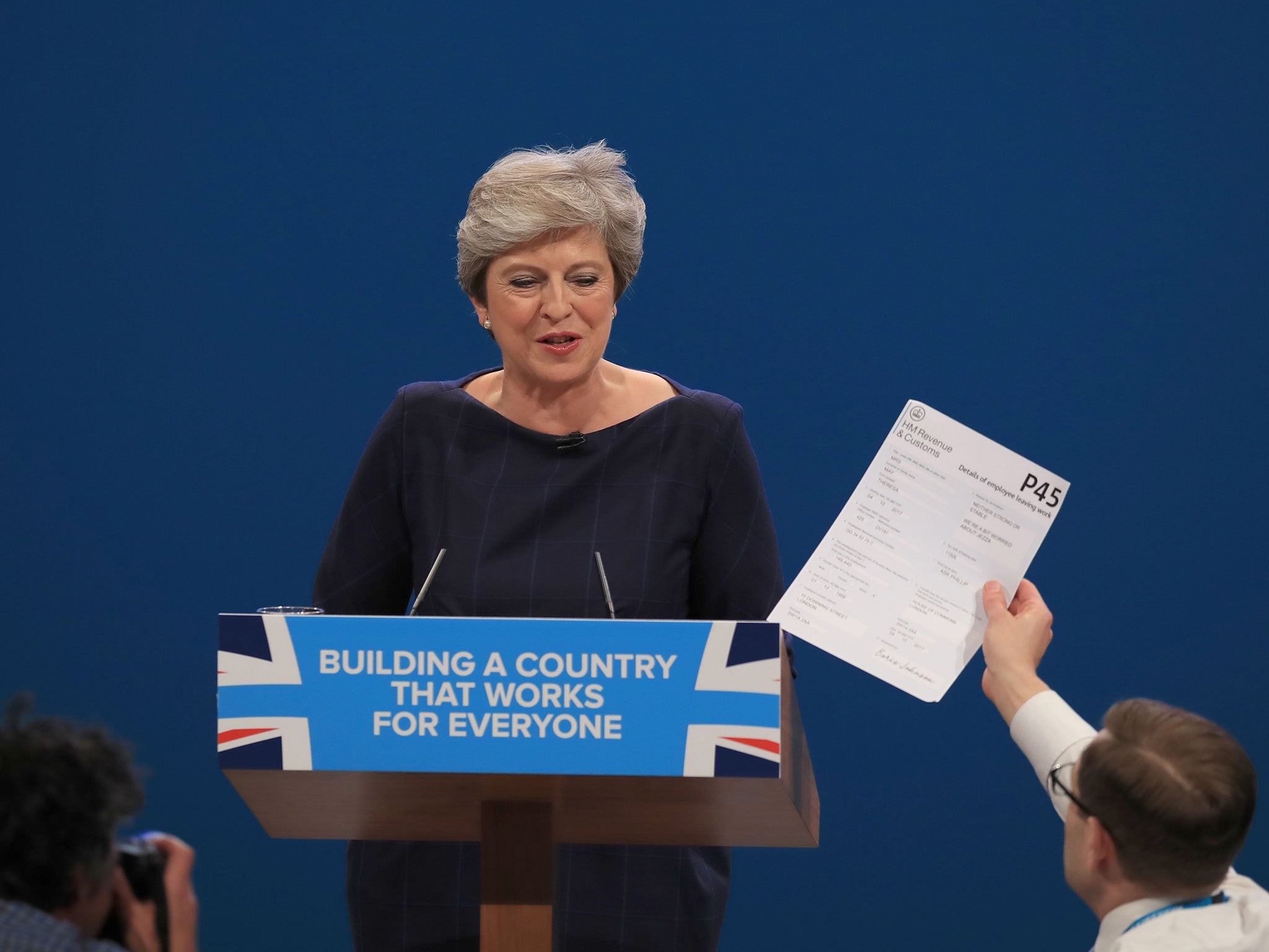 Comedian Simon Brodkin, also known as Lee Nelson hands the Prime Minister a mock P45 during her keynote speech (PA)