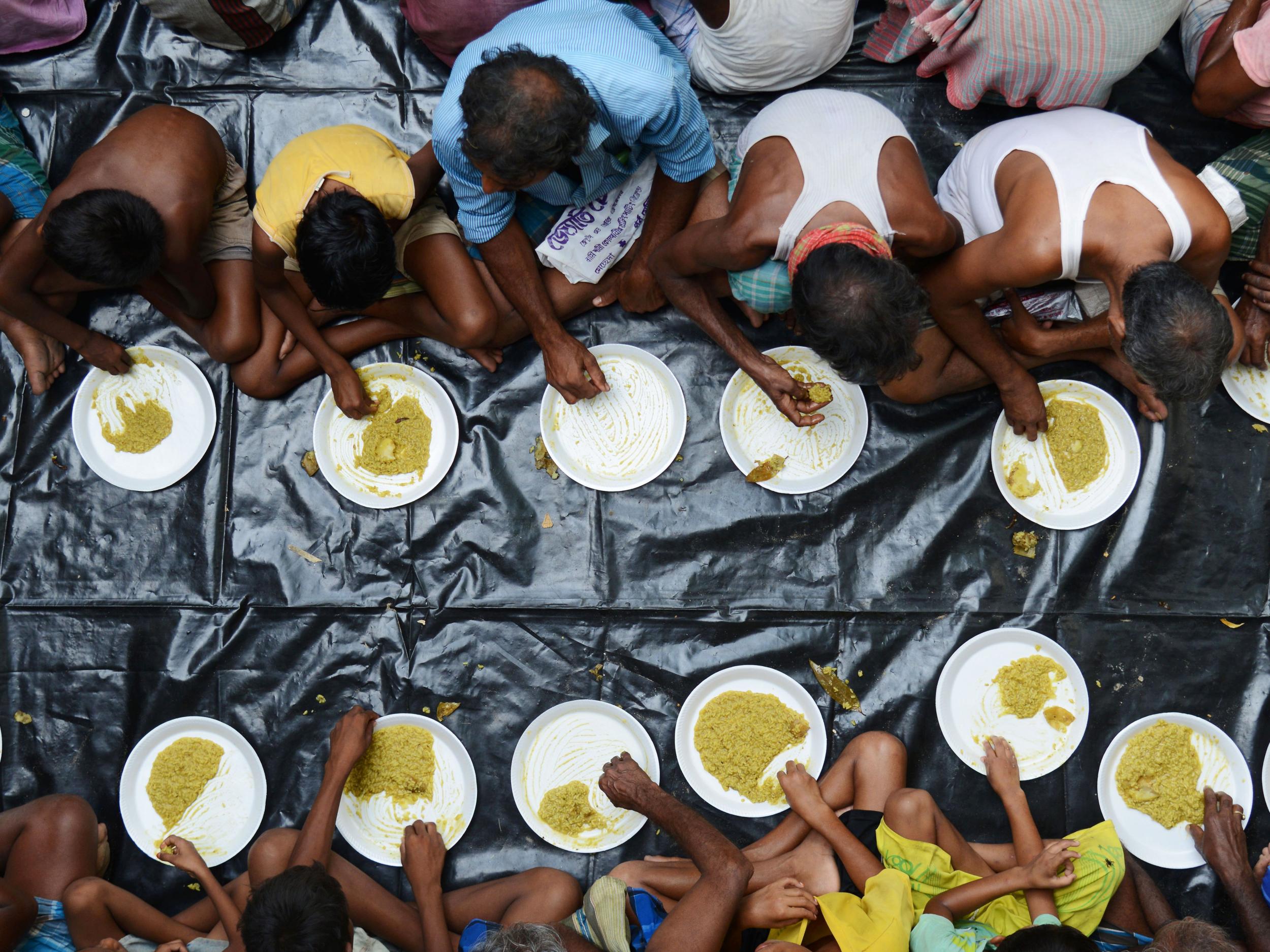 Flood victims in a town near Delhi, in July, exercise the art of eating cross-legged using your hands