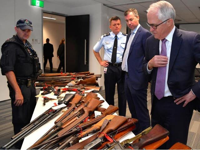 Australian Prime Minister Malcolm Turnbull looks with Federal Police Commissioner Andrew Colvin and Justice Minister Michael Keenan at a firearms on display in Sydney