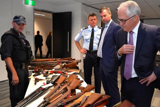Australian Prime Minister Malcolm Turnbull looks with Federal Police Commissioner Andrew Colvin and Justice Minister Michael Keenan at a firearms on display in Sydney