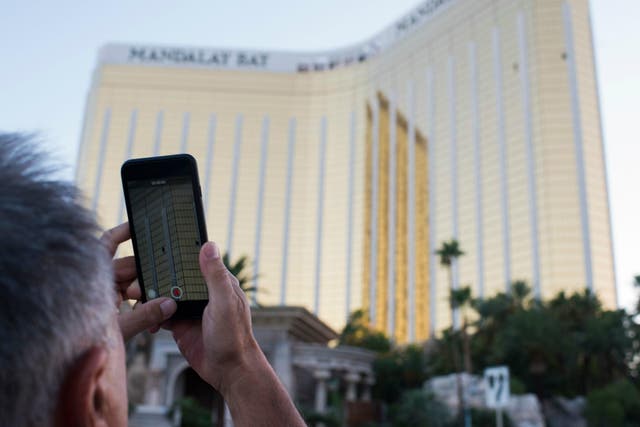A man on the Las Vegas Strip 4 October 2017 films on his phone the two broken windows of the Mandalay Bay hotel from which killer Stephen Paddock let loose the worst mass shooting in modern American history three days prior.