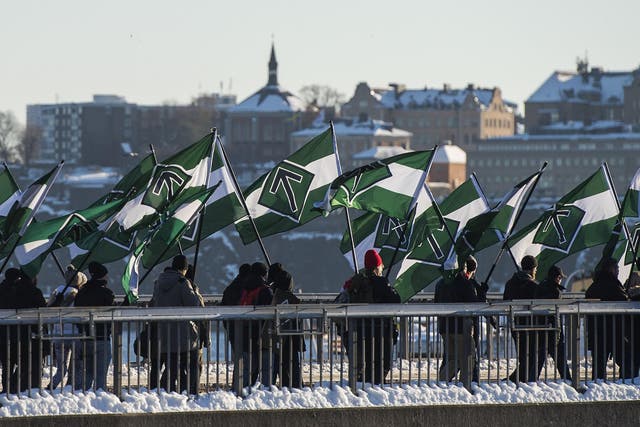 Nordic Resistance Movement supporters marching with flags bearing their 'Tyr rune' logo