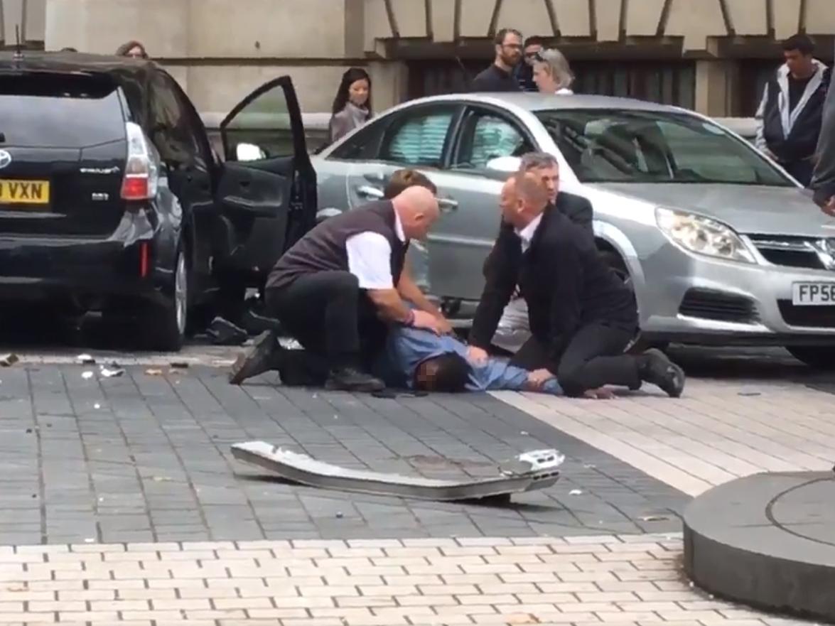 Police pin down a man, believed to be the driver, following the accident outside the museum