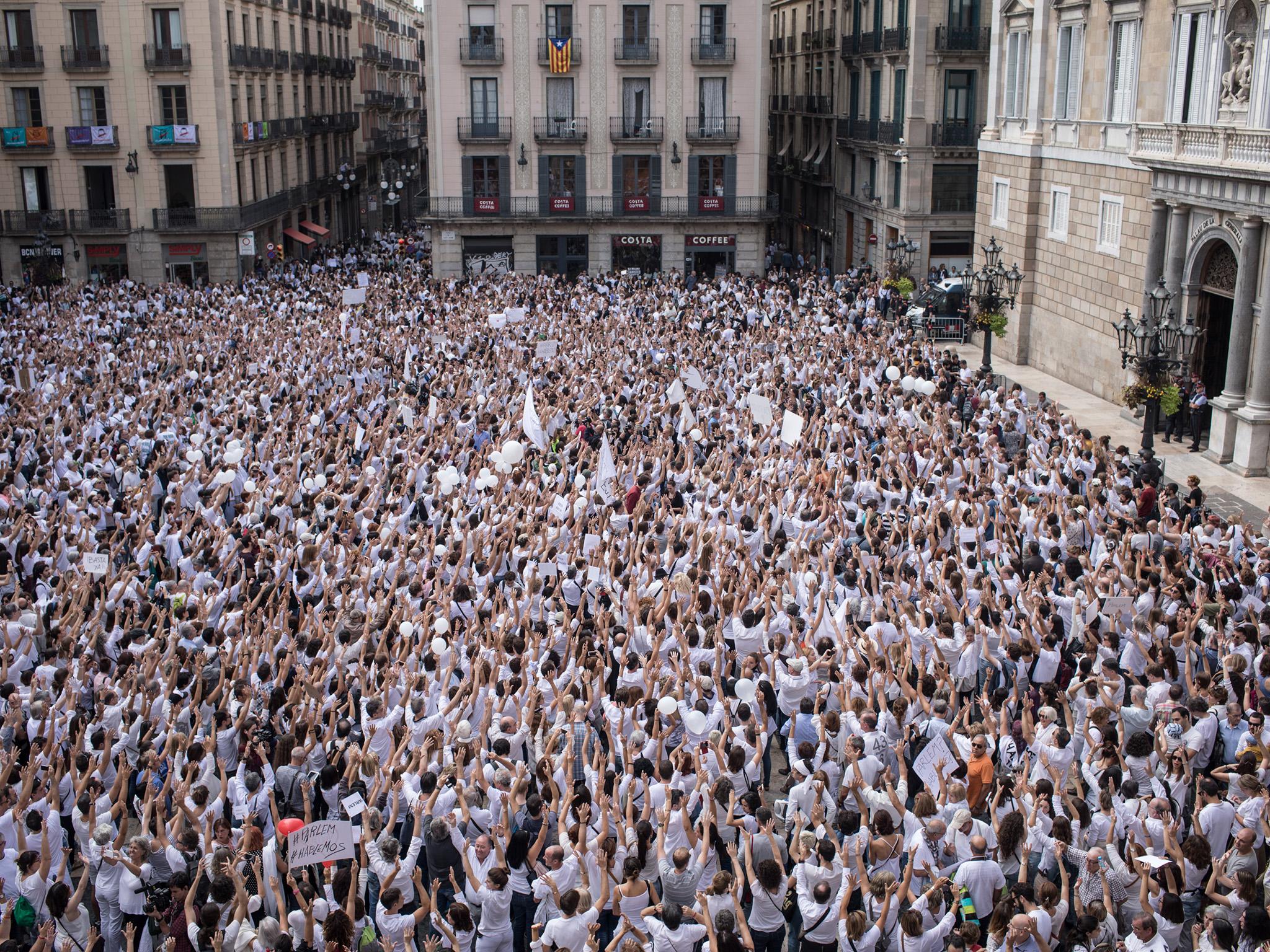 Thousands of people, dressed in white gather and chant the slogan “lets talk” outside the Barcelona city hall (Getty)