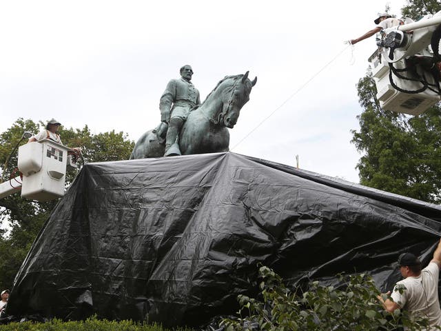 City workers drape a tarp over the statue of Confederate General Robert E Lee in Emancipation Park, where white nationalists gathered this weekend
