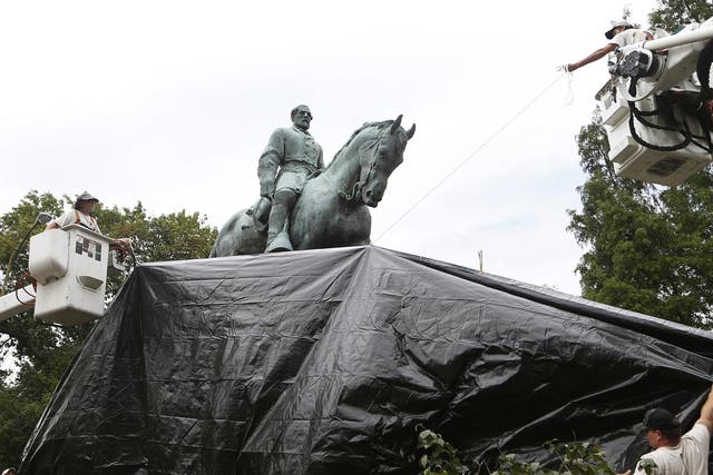 City workers drape a tarp over the statue of Confederate General Robert E Lee in Emancipation Park, where white nationalists gathered this weekend