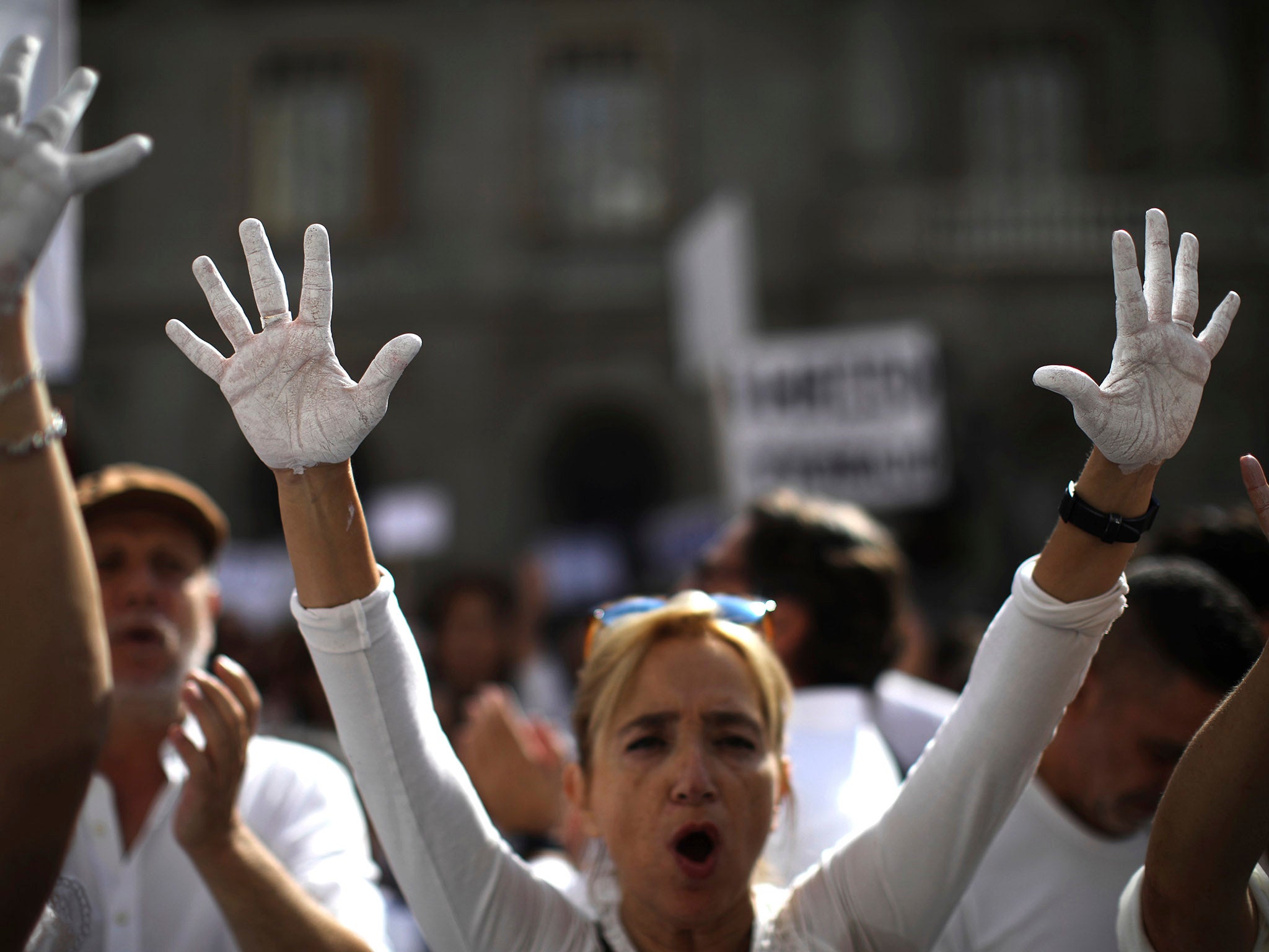 People raise their hands painted in white, to symbolise they are in favour of talks, in Sant Jaume Square in Barcelona