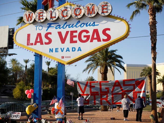 People sign a banner near the "Welcome to Fabulous Las Vegas" sign following the Route 91 music festival mass shooting