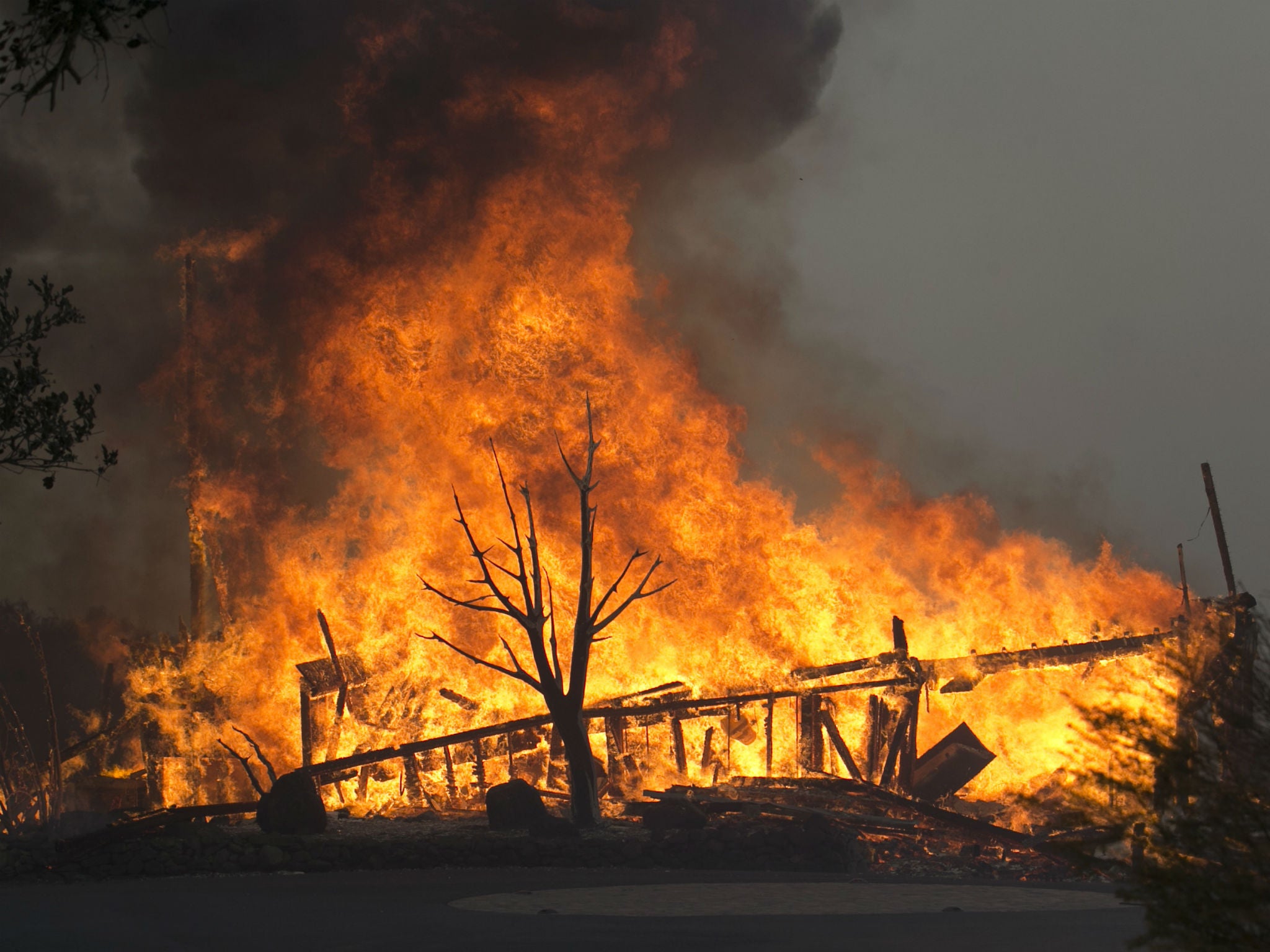 Flames from a wildfire consume a home Monday, Oct. 9, 2017, east of Napa, Calif