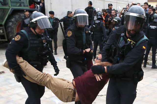 Spanish Guardia Civil guards drag a man outside a polling station in Sant Julia de Ramis