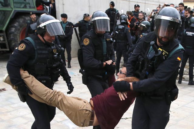 Spanish Guardia Civil guards drag a man outside a polling station in Sant Julia de Ramis