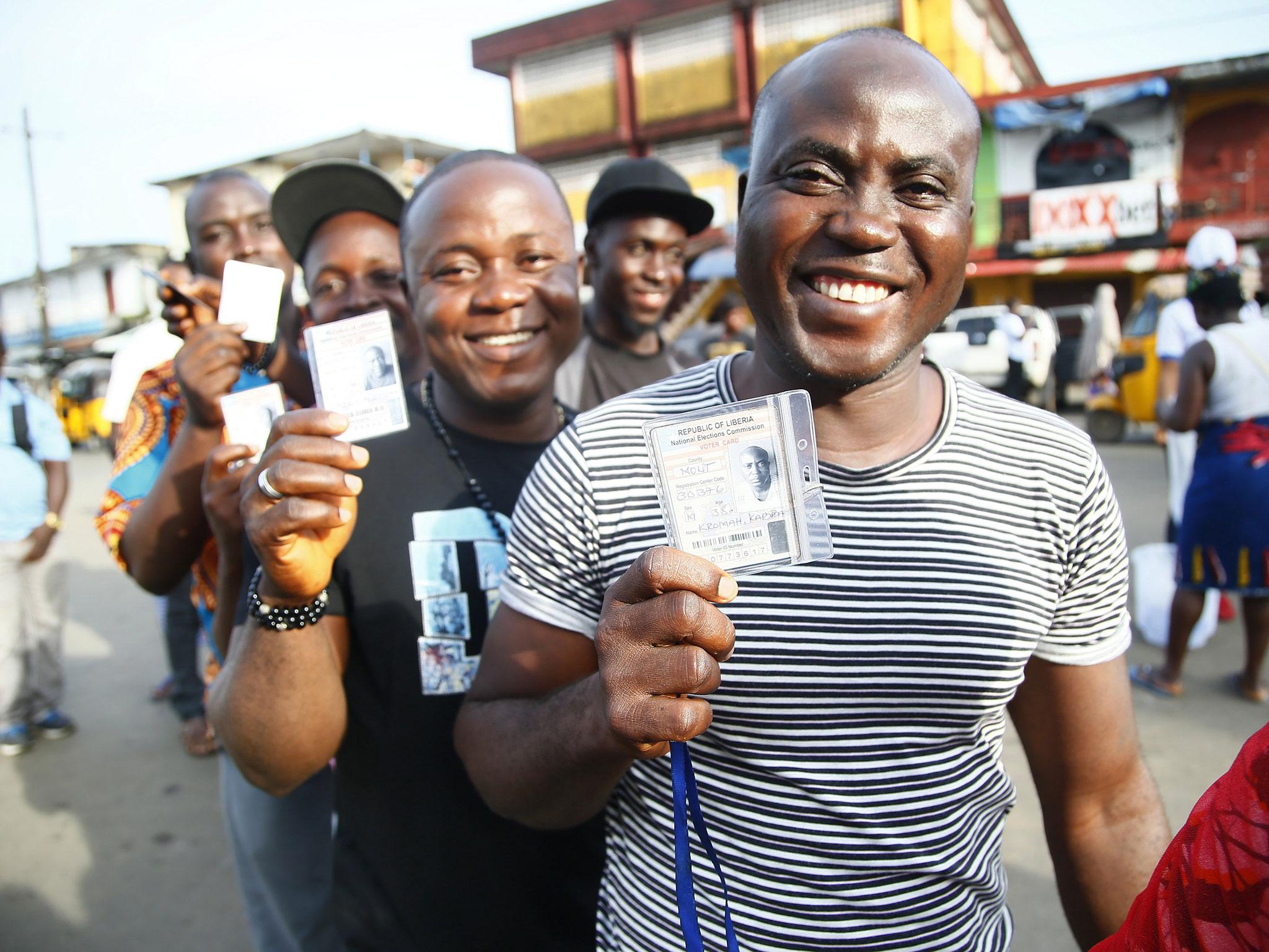 Liberians display voter cards during the presidential and general election in West Point, Monrovia