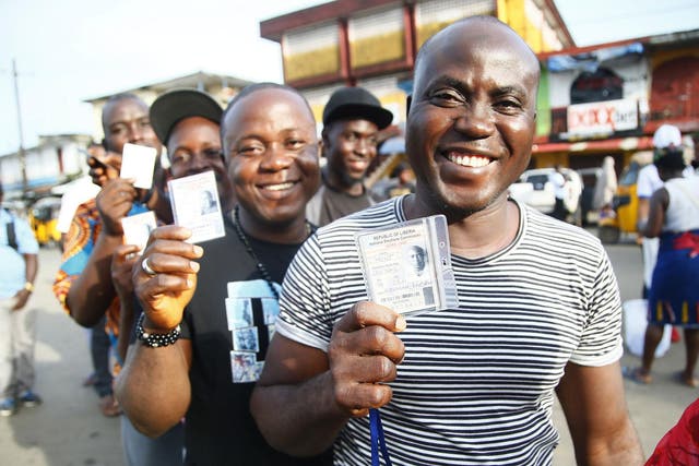 Liberians display voter cards during the presidential and general election in West Point, Monrovia