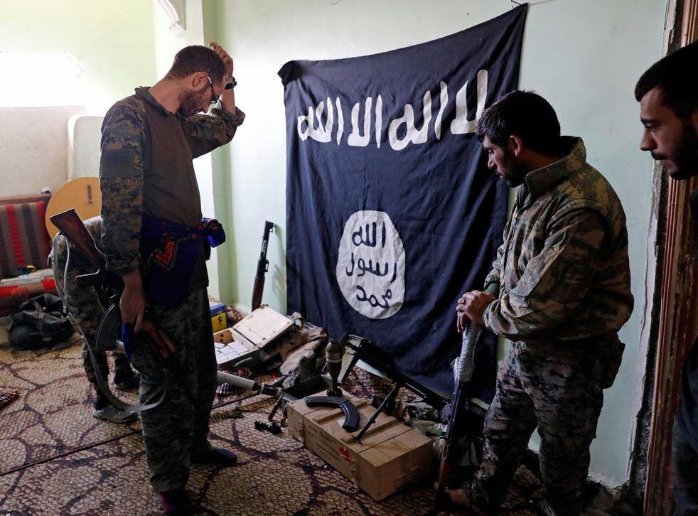 Fighters of Syrian Democratic Forces inspect weapons and munitions recovered at the former positions of the Isis militants inside a building at the frontline in Raqqa