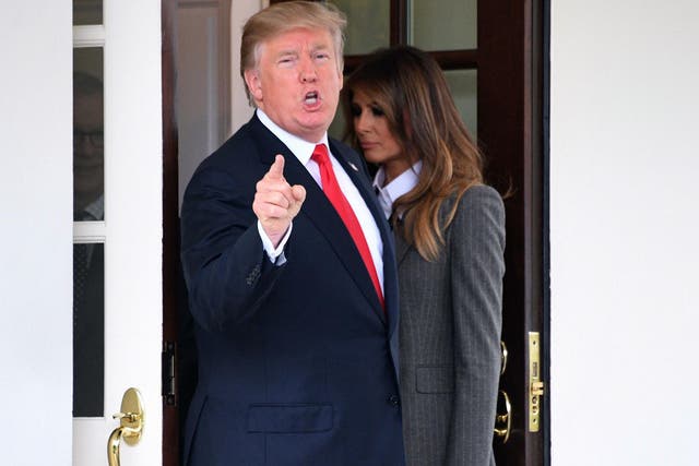 US President Donald Trump answers a question from the press as First Lady Melania Trump walks back into the White House on 11 October 2017.